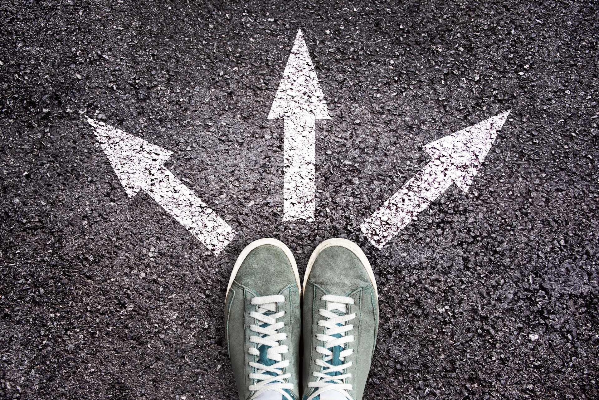 Shoes and arrows pointing in different directions on asphalt floor